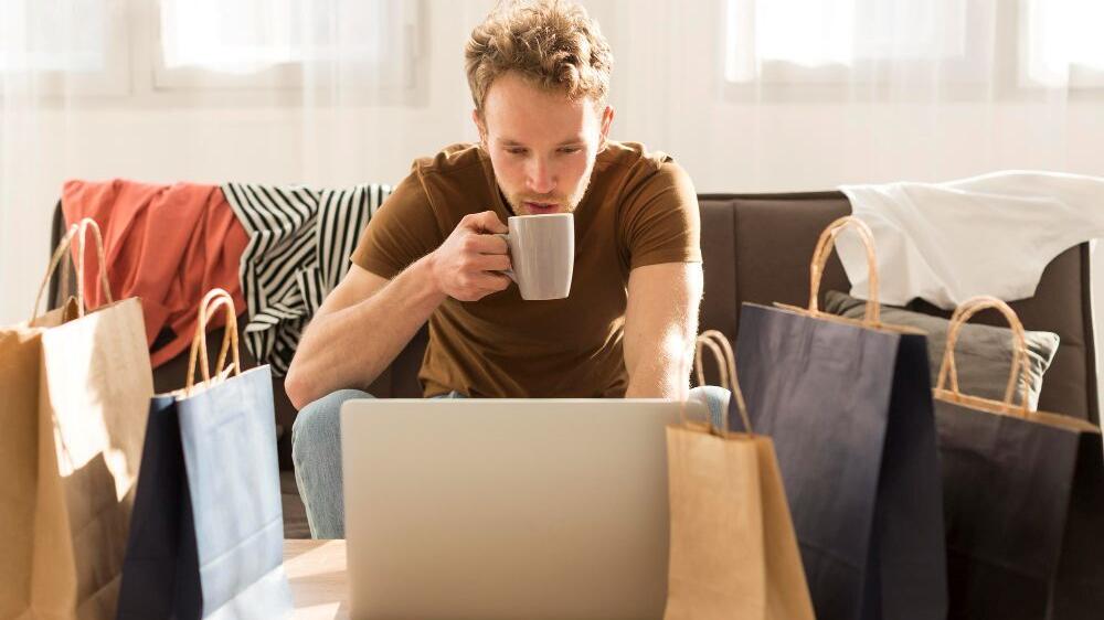 men buying clothes onsline with a cup of coffe